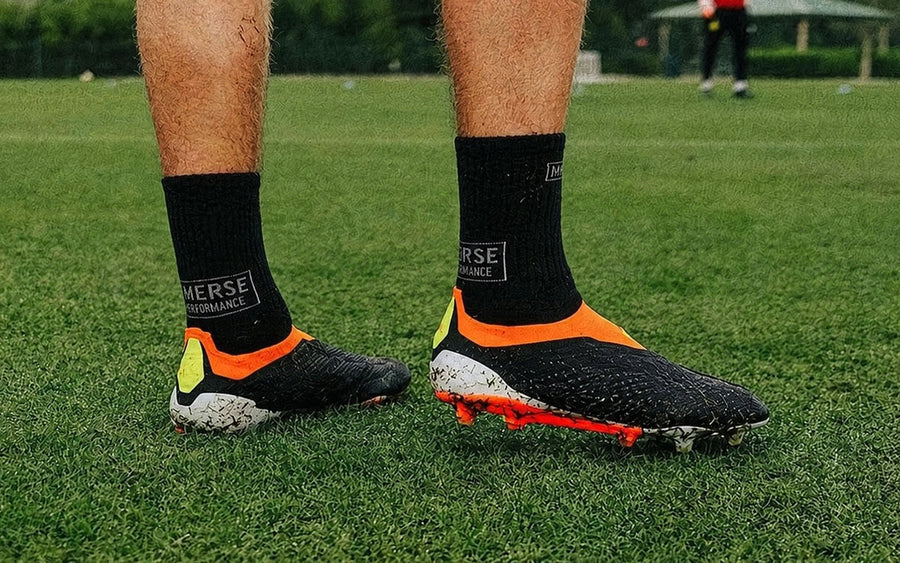 Black Immerse GRIP crew socks worn with football boots on the pitch