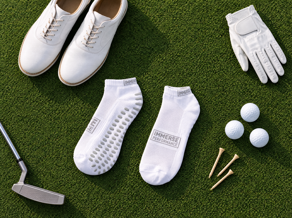 Immerse GRIP ankle socks laid out with golf shoes, glove, balls and tees on the green